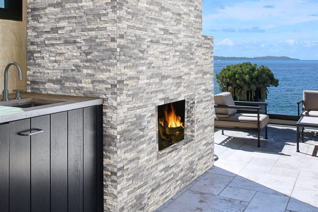Outdoor kitchen with stacked stone fireplace and ocean view